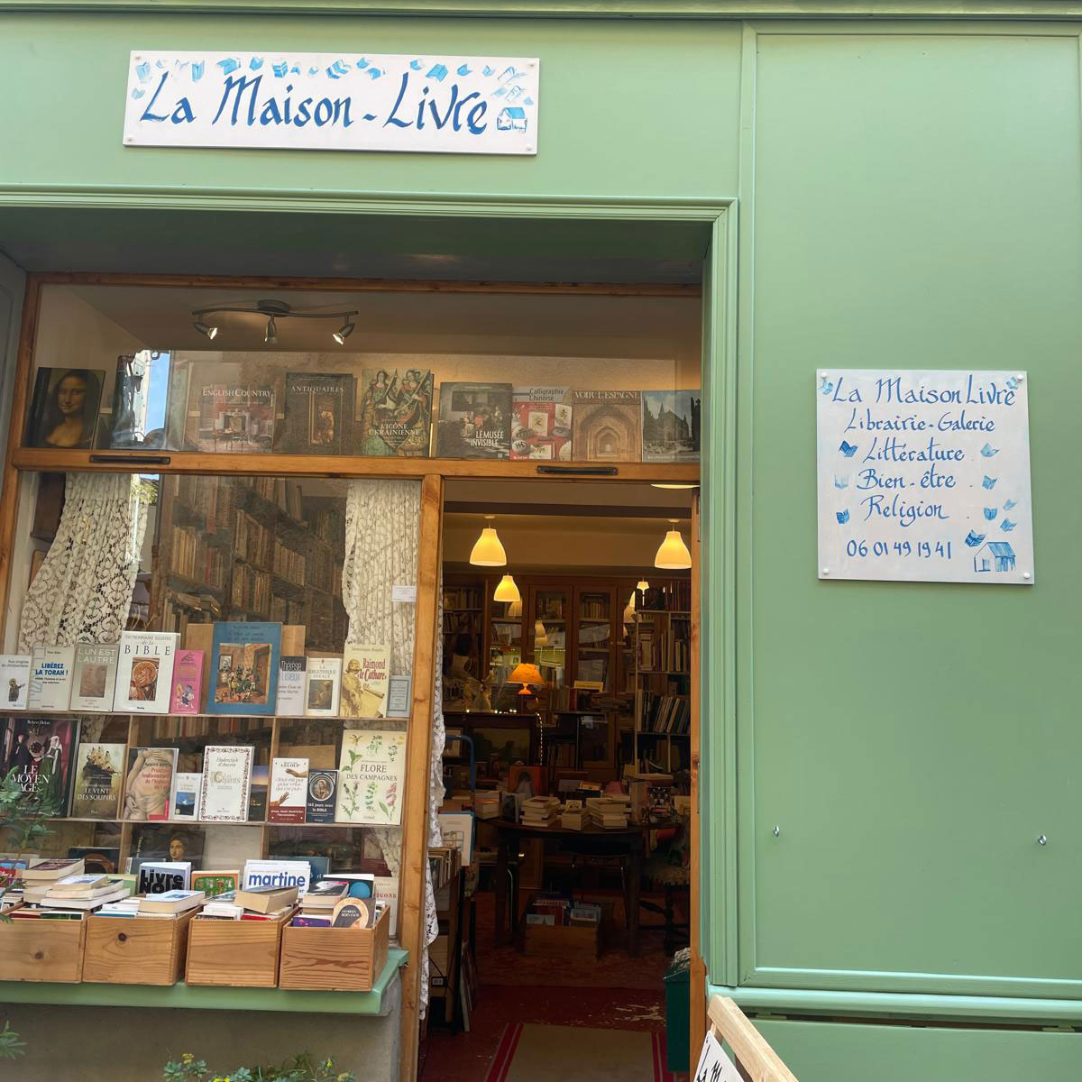 Façade verte de la librairie La Maison Livre à Montolieu, avec son enseigne.